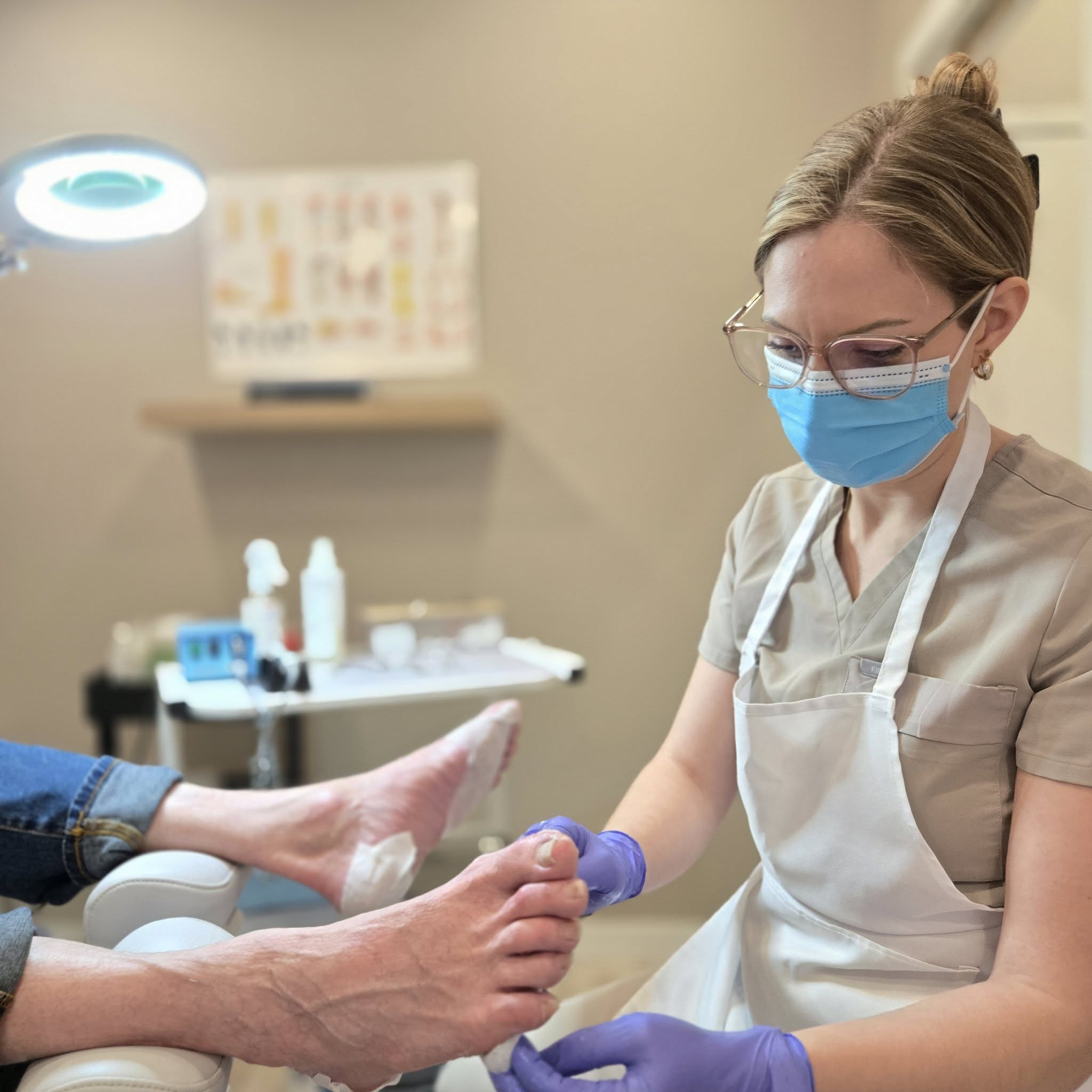 Maude Ferguson, masque et gants, prodiguant un soin des pieds en clinique